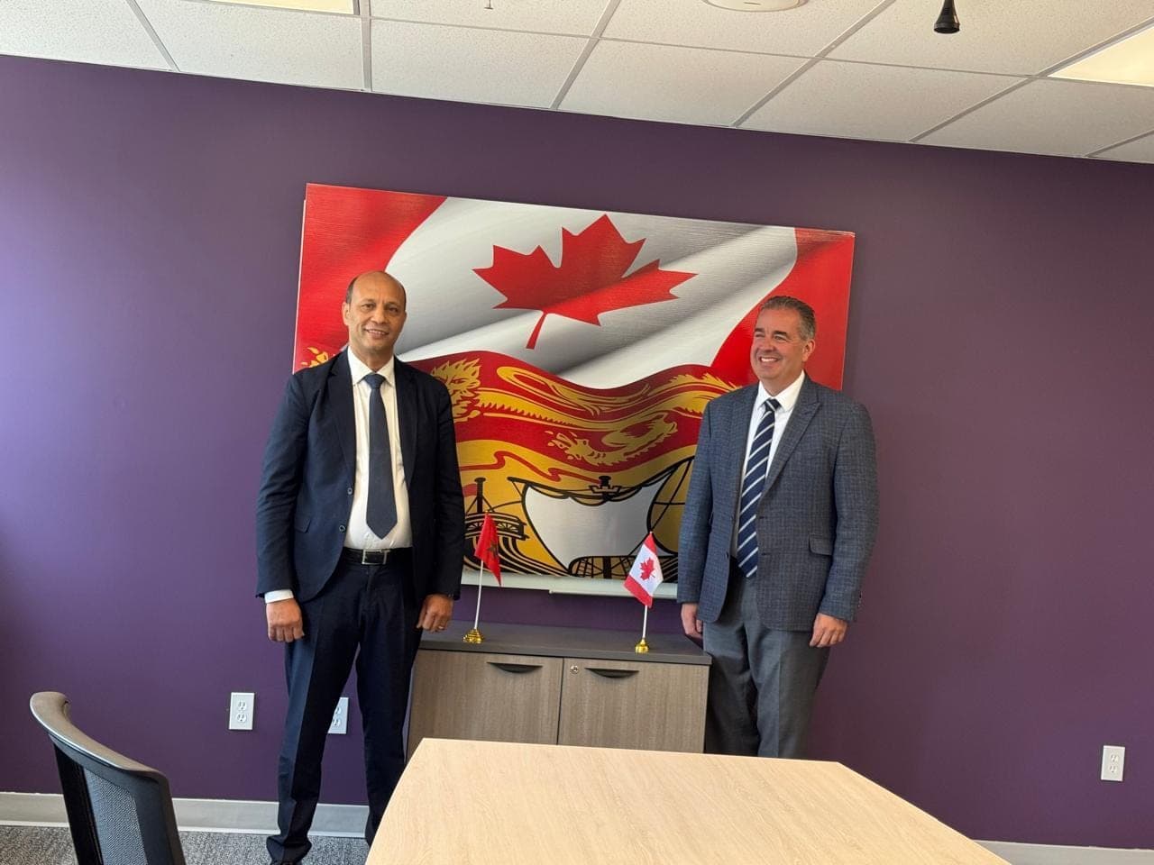 Devant les drapeaux du Canada et du Nouveau-Brunswick